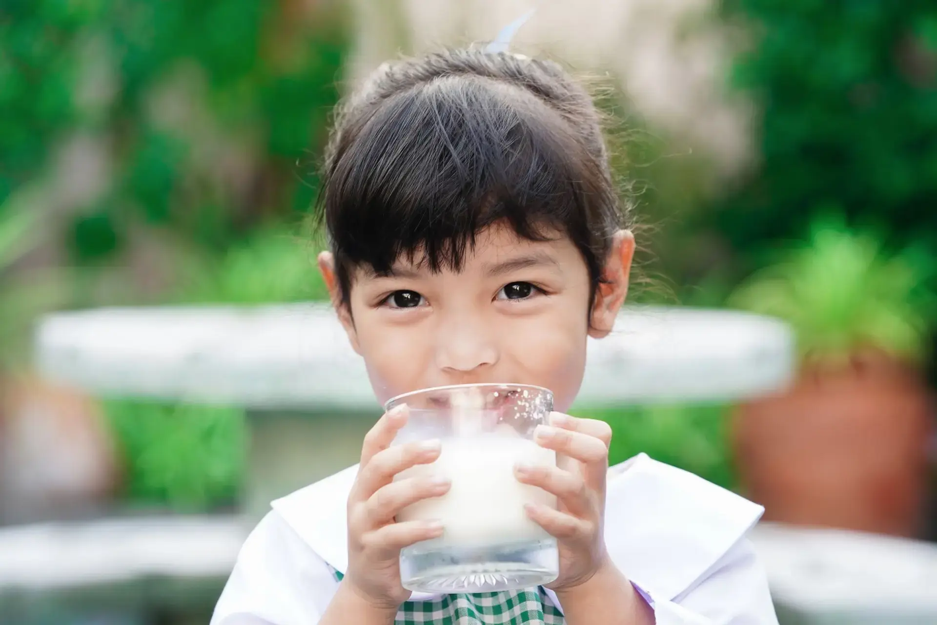 Batang naka-school uniform na umiinom ng gatas.